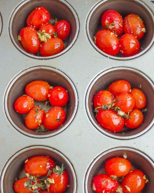 cocktail tomatoes, chopped garlic and herbs piled into the bottom of muffin tin molds