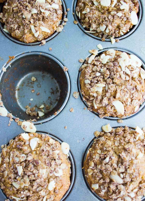 Whole Wheat Apple Cinnamon Muffins in a muffin tin with one muffin missing