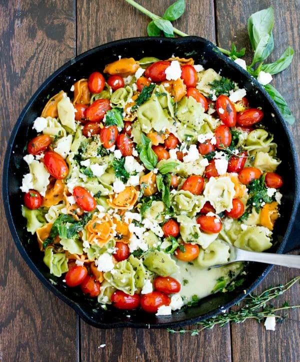 overhead shot of a black skillet with 10 Minute Greek Feta Cheese Tortellini and cocktail tomatoes