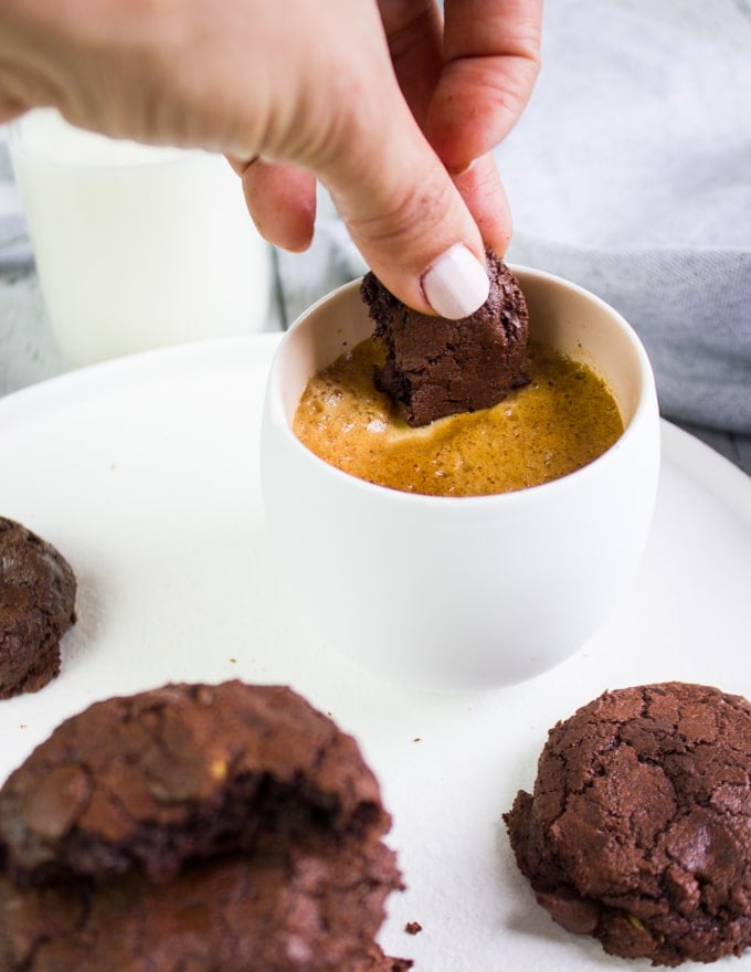 A hand dipping brownie cookies in coffee