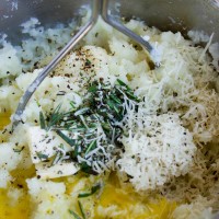 potatoes being mashed with herbs and parmesan