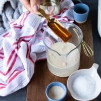 Pouring honey into a cup with warm water and yeast to proof the yeast.