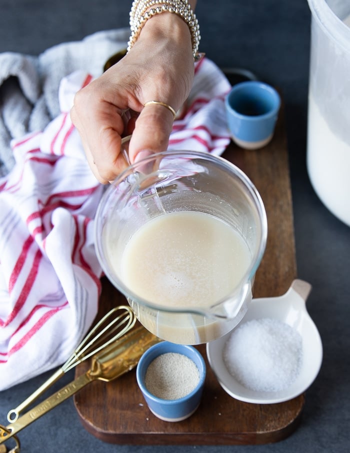 a hand holding the water and yeast mixture showing that the yeast is active