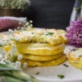 stacks of potato pancakes on a plate with a top bitten pancake showing the inside fluffy mashed potato texture