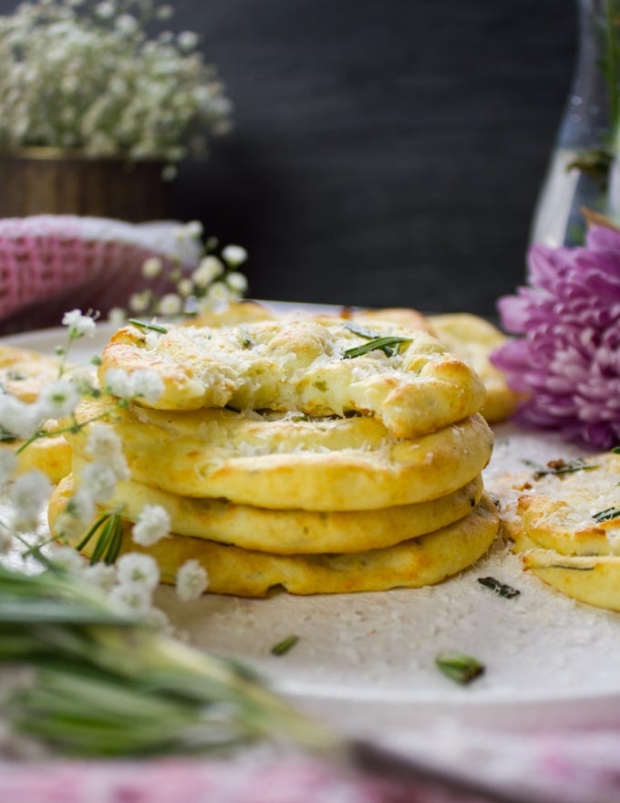 stacks of potato pancakes on a plate with a top bitten pancake showing the inside fluffy mashed potato texture