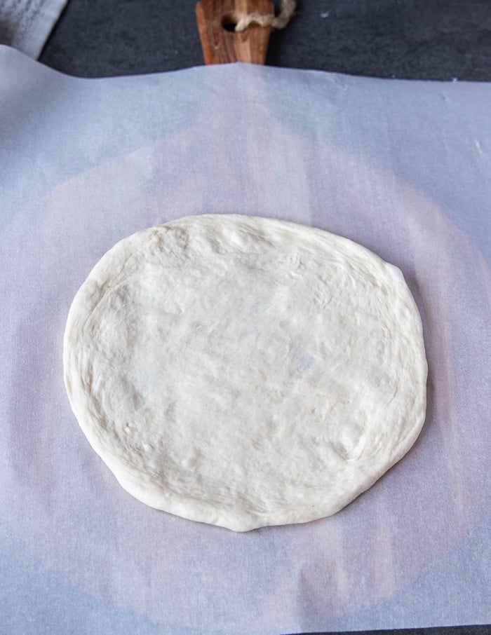 a pizza dough recipe shaped into a circle and placed on a pizza board
