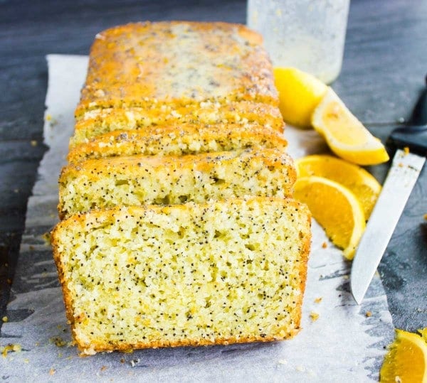 Side view of a moist and fluffy Citrus Poppy Seed Loaf cake with orange slices on the side