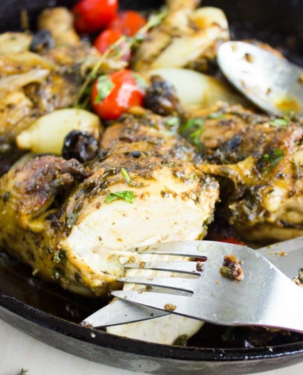 a piece of juicy chicken breast being cut from a Garlic Herb Roast Chicken in a skillet