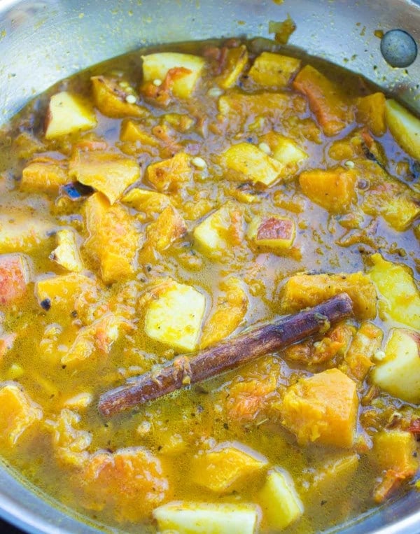 mediterranean soup simmering in a pan showing the ingredients and cinnamon stick 