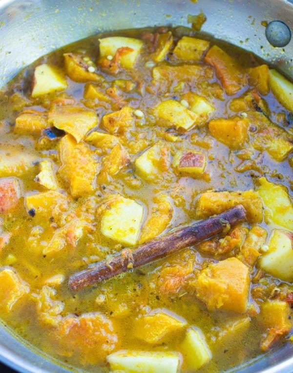 mediterranean soup simmering in a pan showing the ingredients and cinnamon stick 