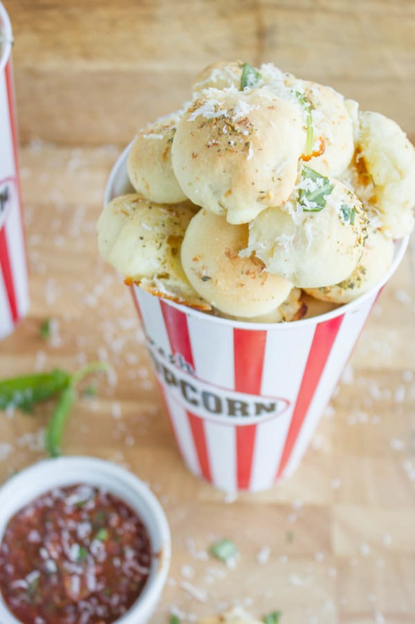 Pizza Popcorn Bites in a white and red popcorn cup with a tomato dip on the side