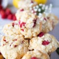 stacked up raspberry muffins over one another with fresh rasberries around them and some lemons in the background on a white board