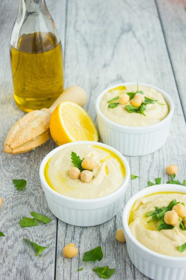 three small dishes with Ultimate Hummus Dip with a bottle of olive oil in the background