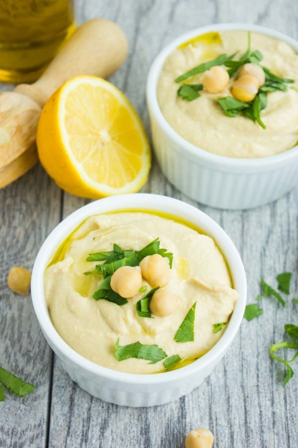 close-up of a small dish of hummus dip topped with parsley and chickpeas