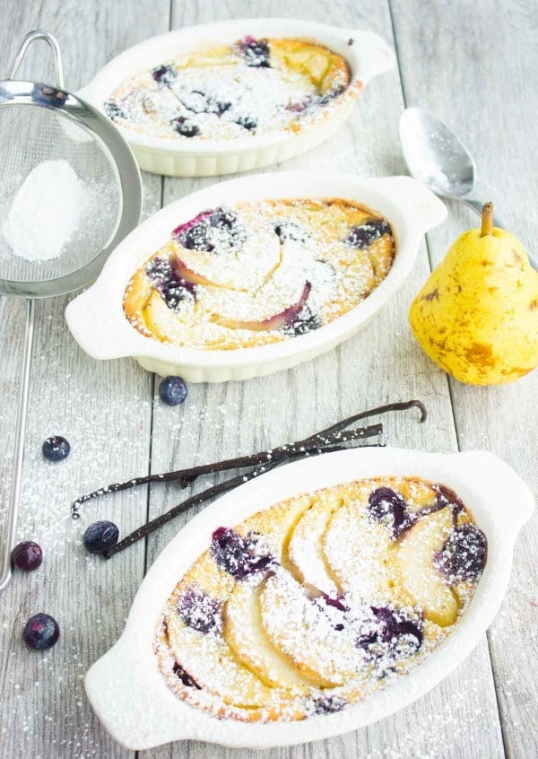 Vanilla Blueberry Pear Clafoutis served in three individual ramekins, dusted with icing sugar