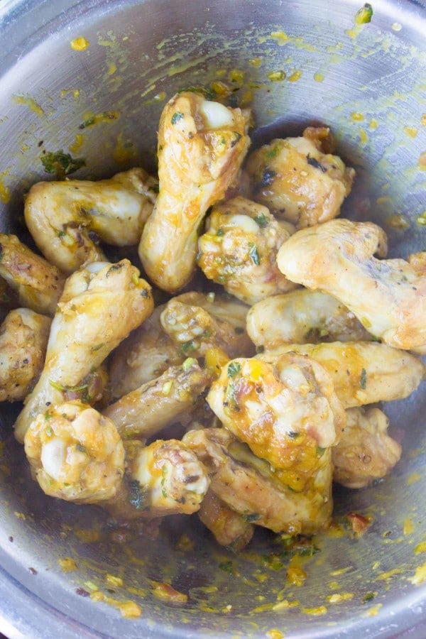 pre-baked chicken wings being tossed in mango chutney