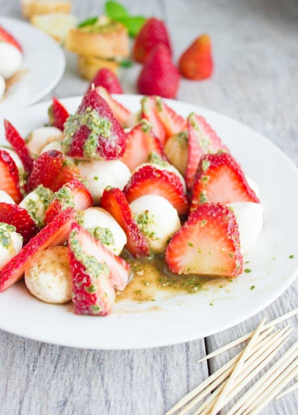 half-eaten plate of Strawberry Caprese Salad smothered in pesto.