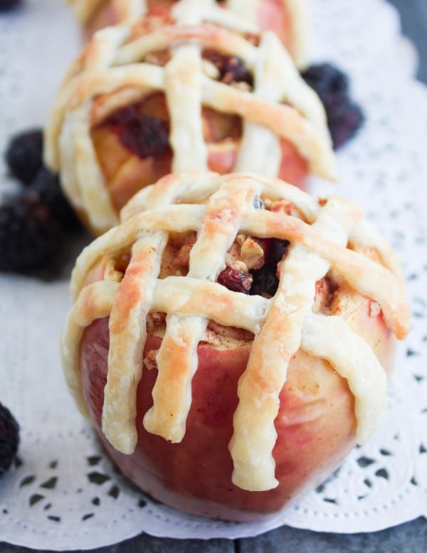 Apple Pie Stuffed Apples with golden brown pie crust lattice on top served on a cake doily