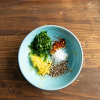 A bowl with the flavoring of calamari including lemon zest, chilli flakes, salt, pepper and herbs