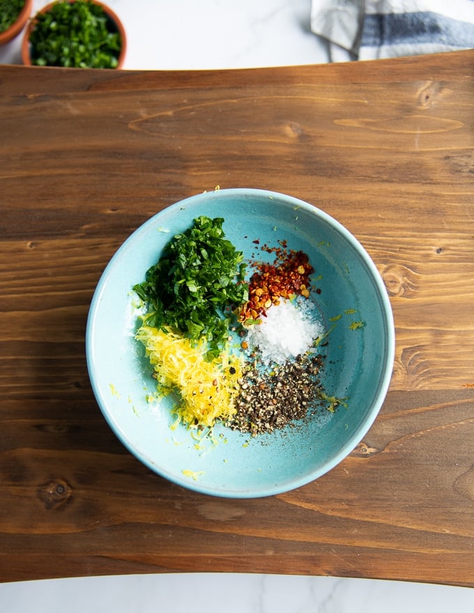 A bowl with the flavoring of calamari including lemon zest, chilli flakes, salt, pepper and herbs