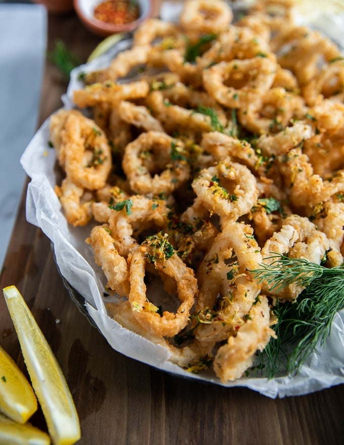 close up of the fried calamari showing the crispy calamari texture with the herb topping and some lemon wedges