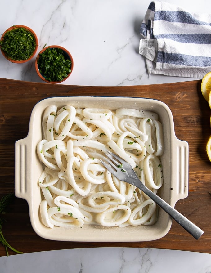 Squid rings in a buttermilk or milk mixture soaking to tenderize before coating and frying