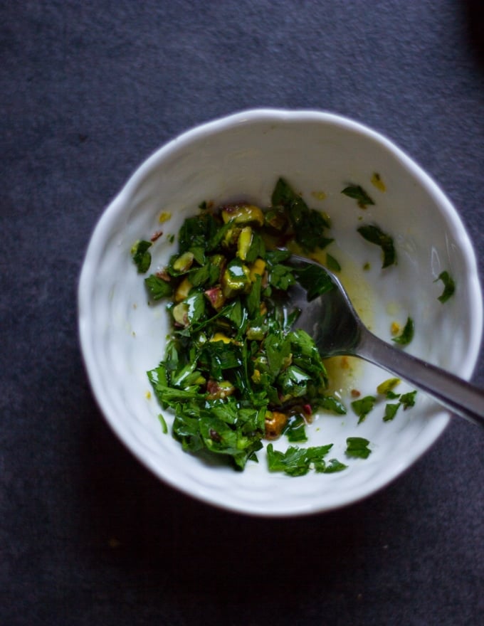 a bowl with a mixture of parsley, pistachio chopped, lemon and olive oil for a pistou topping