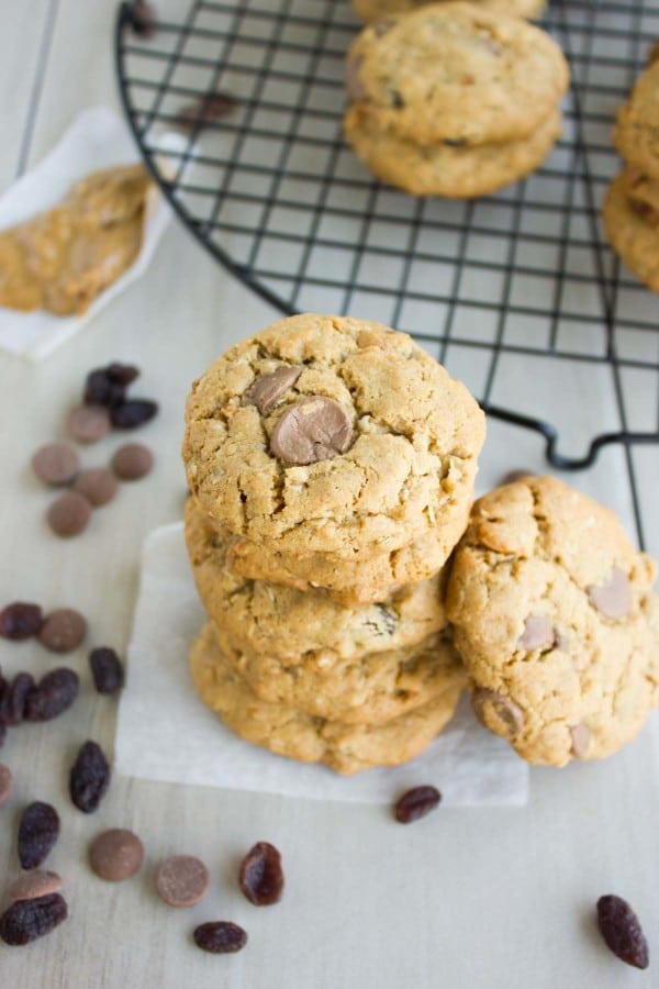 Peanut Butter Chocolate Chip Cookies stacked on top of each other on a piece of parchment paper with some chocolate chips on the side