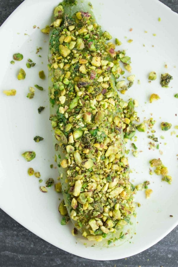 pistachio-crusted fish fillet on a white plate ready to be fried.