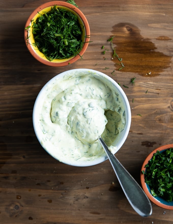 A spoon mixing all tartar sauce ingredients in a small bowl