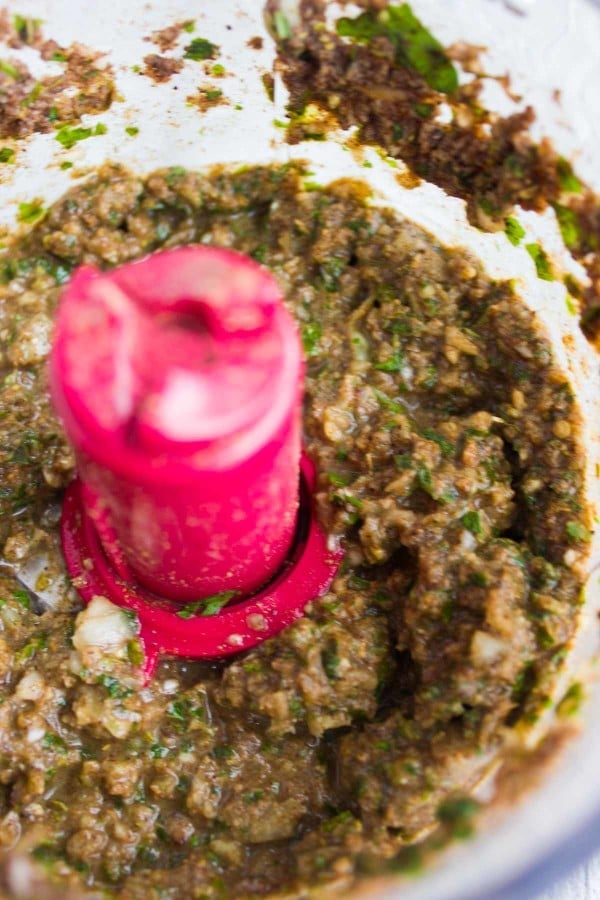 food processor showing minced onions, garlic, herbs and spices