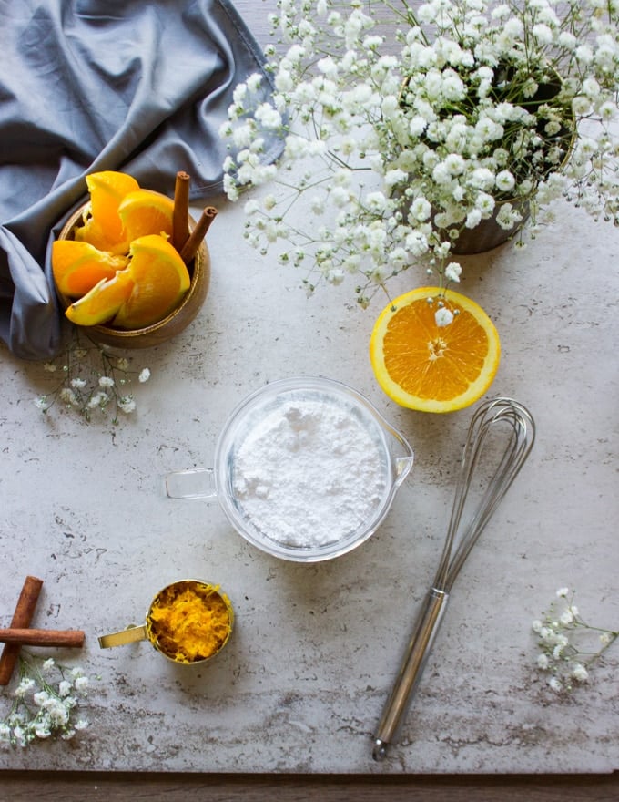 The glaze ingredients. A bowl with the confectioner sugar and a half an orange and a whisk