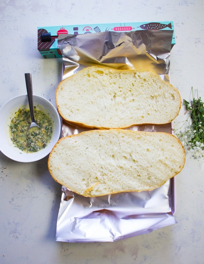 Itlian loaf of bread sliced in half on abaking sheet lined with foil