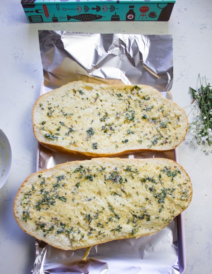 The loaf of spread halves are spread well with the roasted garlic butter mixture and ready to be wrapped