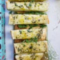 Sliced up garlic bread sticks on a cutting board