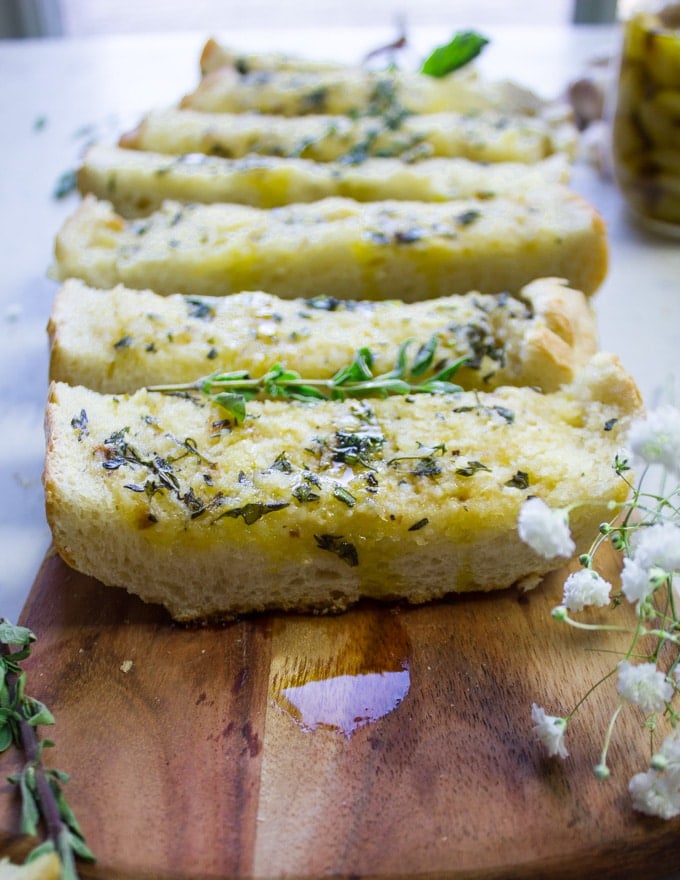 Close up of one piece of garlic bread with herbs on a cutting board