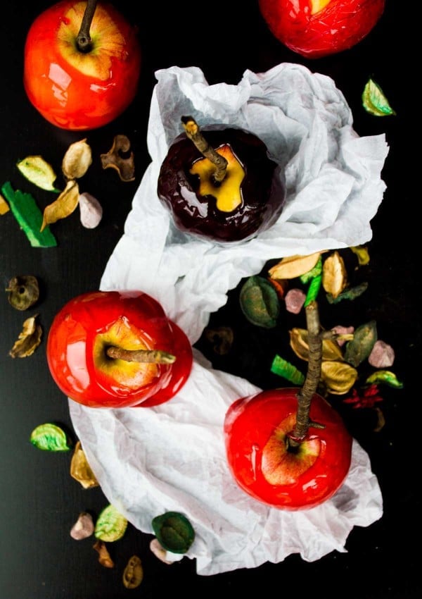 Top view of four red candy apples and one black one for Halloween