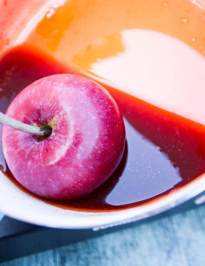 An apple on a stick being dipped in ready boiled candy sugar