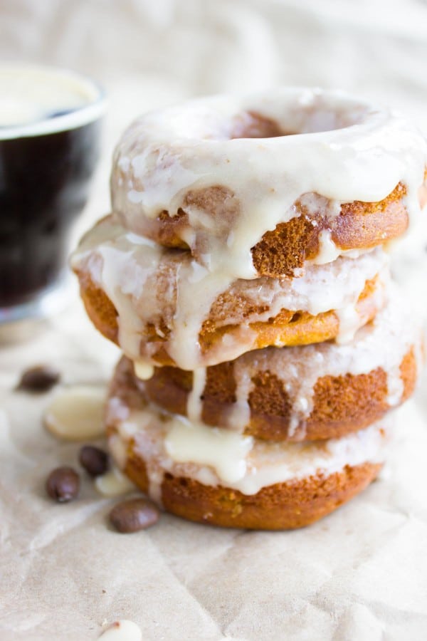 Espresso Glazed Pumpkin Spice Donuts stacked on top of each other with a coffee mug in the background