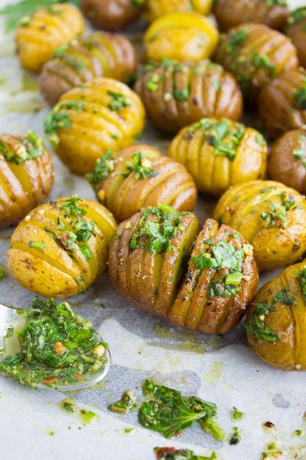 Hasselback-style Herb Roast Potatoes smothered with butter arranged on a tray