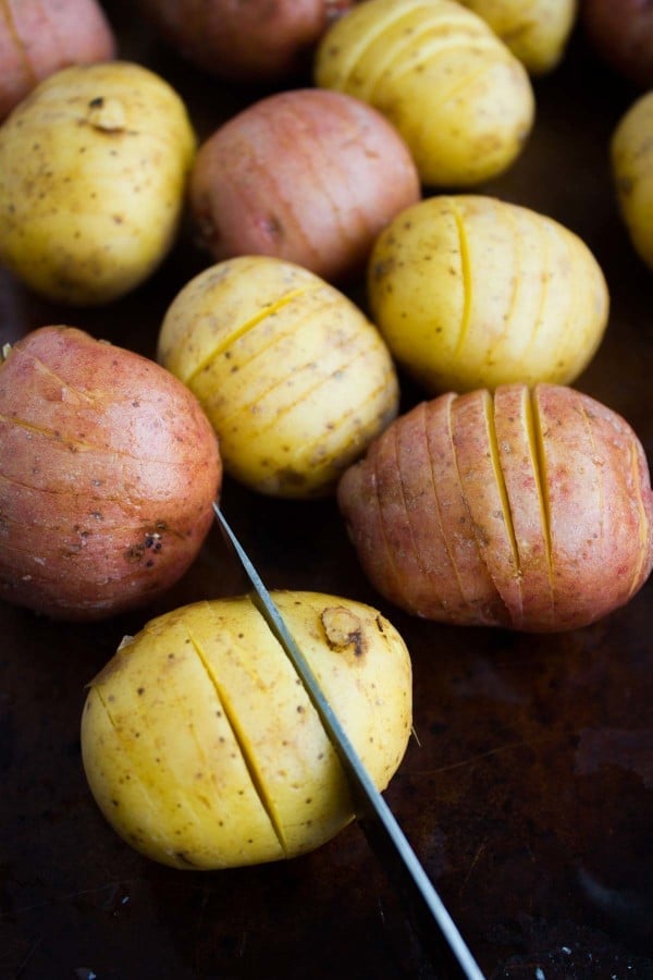 red and yellow potatoes with slits cut into them with a knive