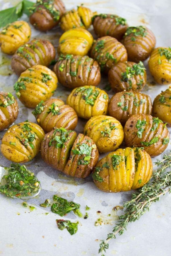 Herb Roast Potatoes smothered with herb butter arranged on a baking tray