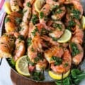 grilled shrimp on a platter with herbs and lemon slices