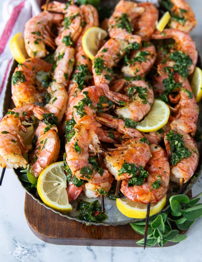 grilled shrimp on a platter with herbs and lemon slices 