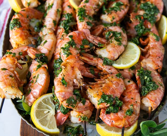 grilled shrimp on a platter with herbs and lemon slices