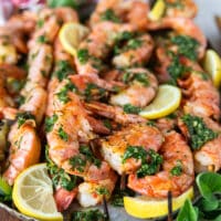 Close up of a grilled shrimp skewer dressed up with herbs and lemon