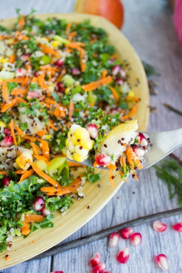 a fork loaded with Quinoa Autumn Harvest Salad held in front of a salad bowl with more quinoa sala
