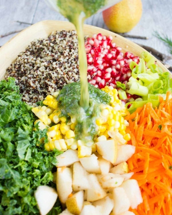 salad dressing being poured on top of a Quinoa Harvest Salad