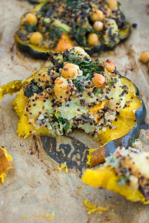 a half eaten acorn squash ring topped with quinoa kale stuffing 
