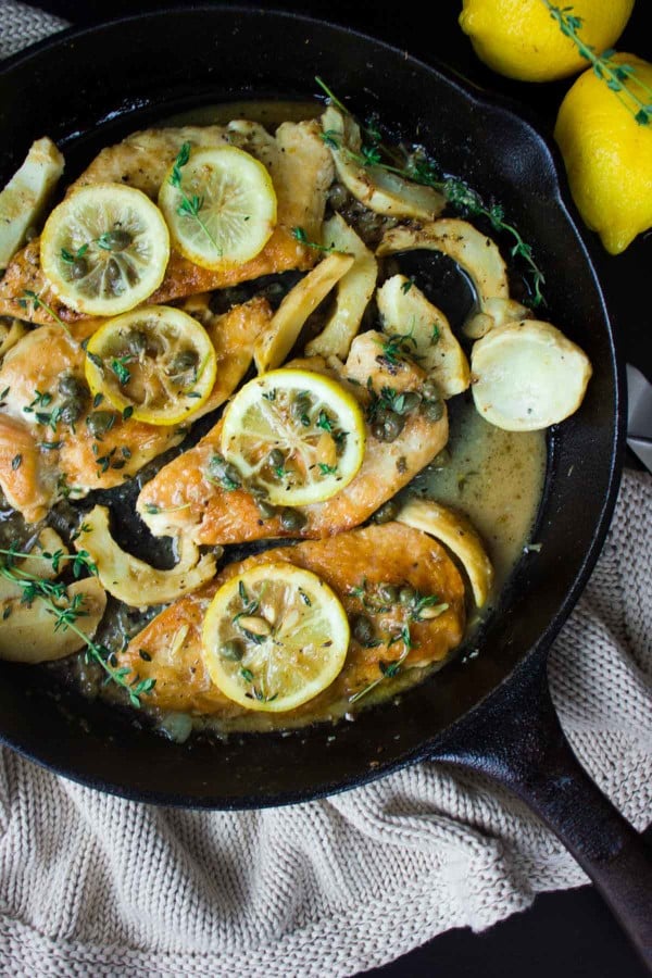 Lemon Caper Artichoke Chicken Piccata served topped with lemon slices, in a skillet